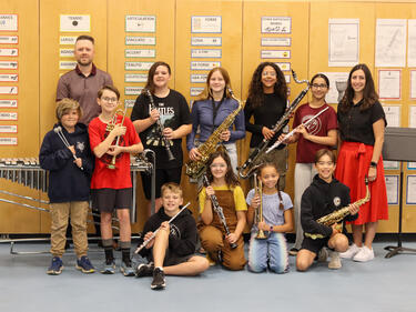 Group of students holding new instruments, alongside their teacher and another adult