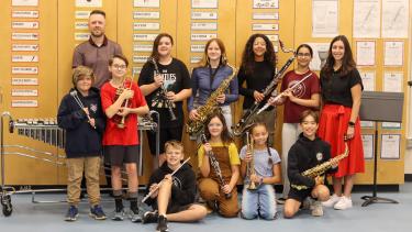 Group of students holding new instruments, alongside their teacher and another adult