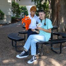 Female secondary student reads book to male elementary student