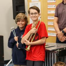 Two students holding instruments and smiling